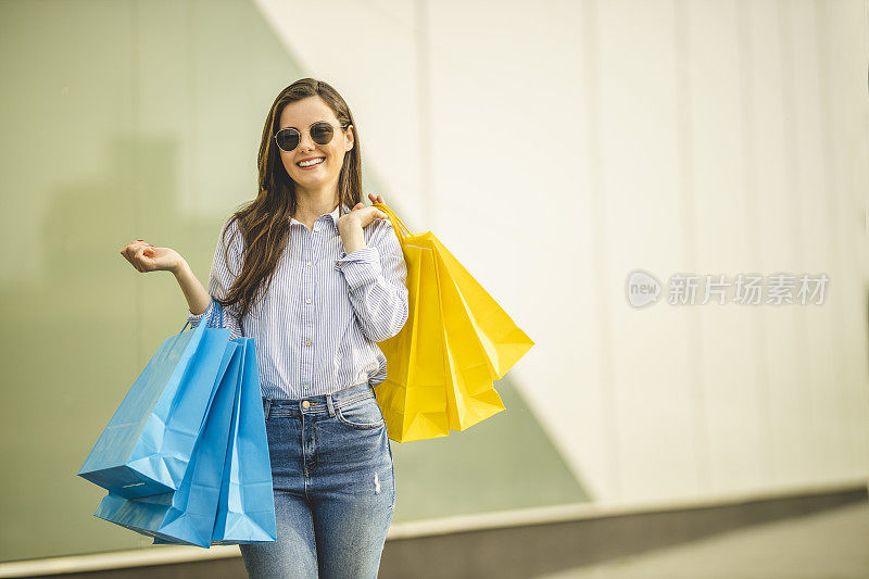 年轻漂亮的女人提着购物袋走路