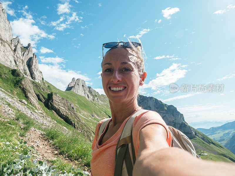 一名女子在瑞士徒步旅行，然后停下来自拍一张全景图