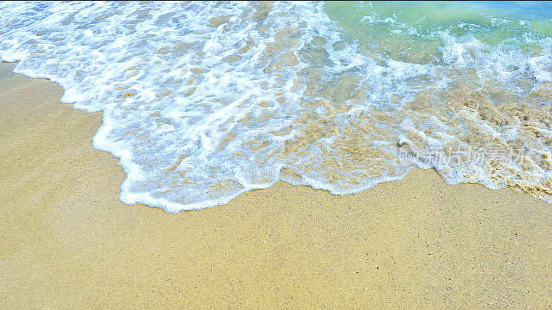海浪卷起白色干净的泡沫冲进海滩