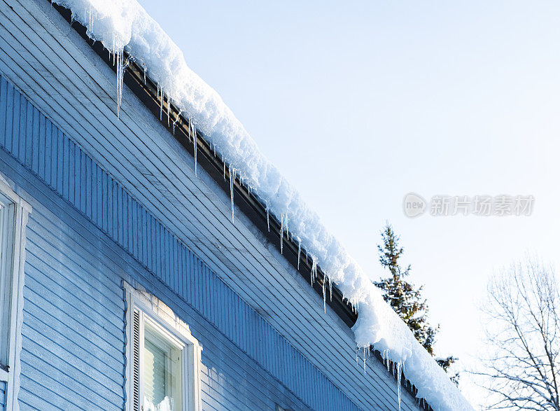 木屋屋顶上的雪和冰柱。春天的季节。