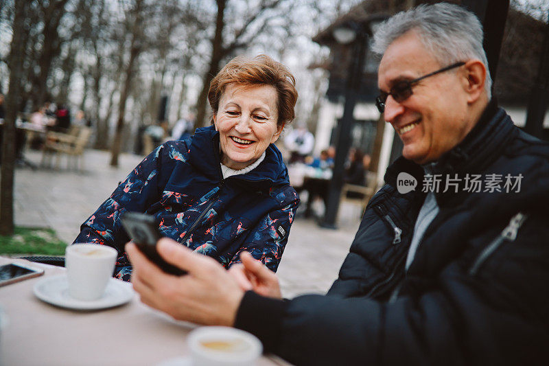 一男一女在咖啡厅里放松，看着社交媒体上的图片