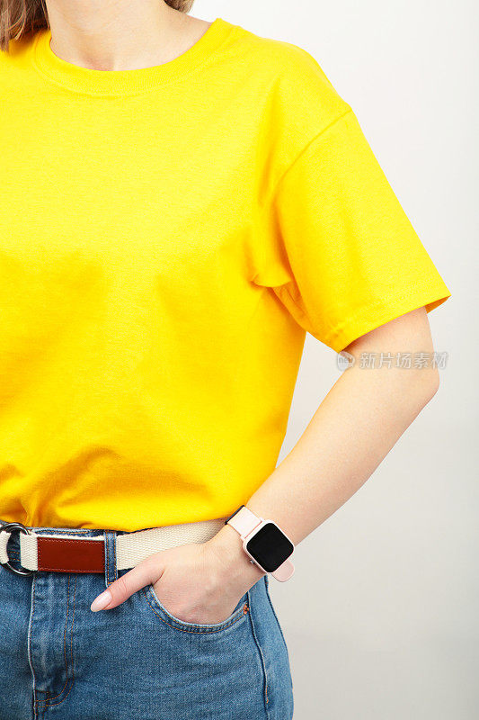 灰色背景上穿着黄色t恤的年轻女孩。t恤设计和人的概念-近距离。