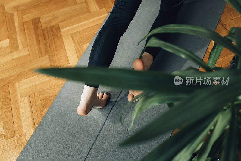 一个在垫子上做瑜伽的匿名女人的腿