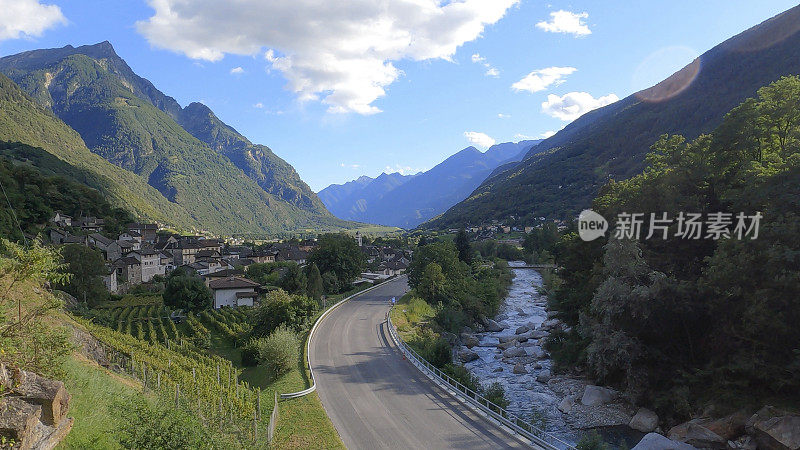 道路蜿蜒穿过郁郁葱葱的山谷，有葡萄园、河流和群山