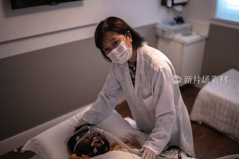 一名医生正在做多导睡眠检查(睡眠研究)——戴着防护面罩