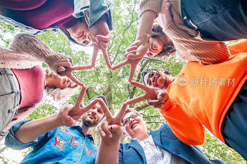 一群z世代的年轻人围成一个圈，用他们的手指组成一颗星星，这是和平的标志，象征着多样性、包容和友谊