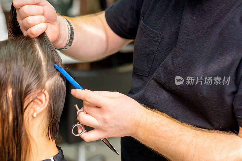 美发师在美发厅近距离用梳子夹住头发，将女性的头发分成几部分。