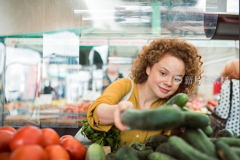 一个可爱的素食女孩在市场上买蔬菜的肖像