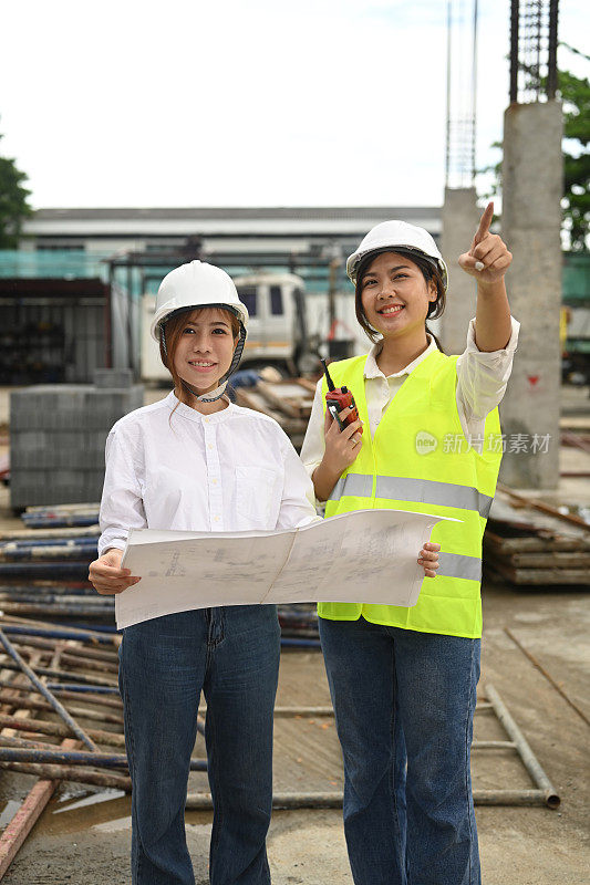 亚洲女建筑师和主管在参观新建筑时讨论计划。