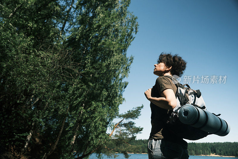 一位女背包客在湖岸徒步旅行