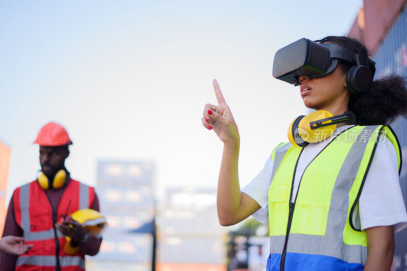非洲裔美国女工程师戴着VR头盔看着集装箱货船。
