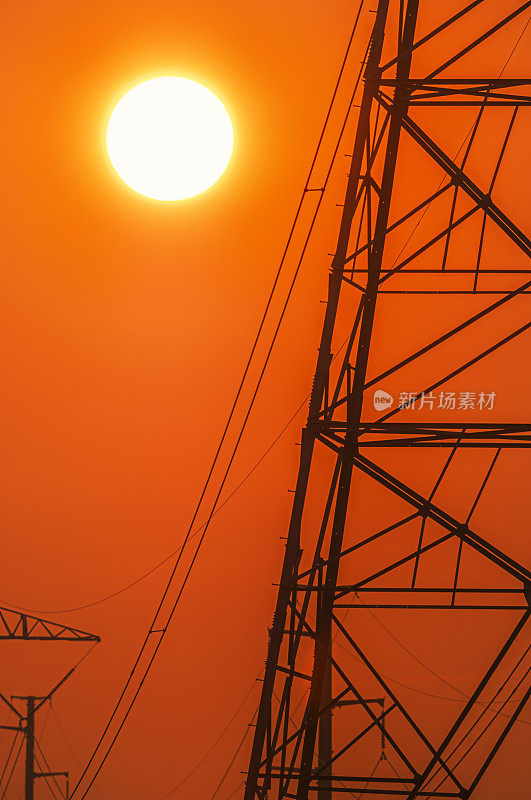 炎炎夏日，太阳落在高压输电塔后面