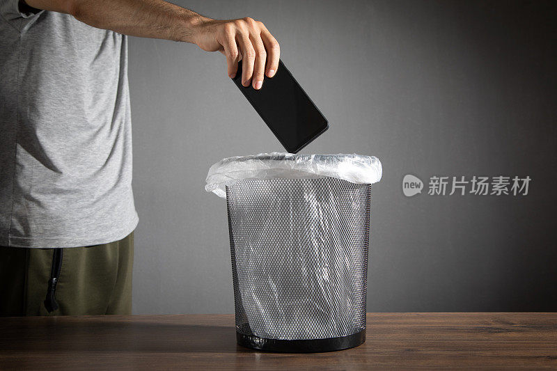 男性将智能手机扔进垃圾桶。