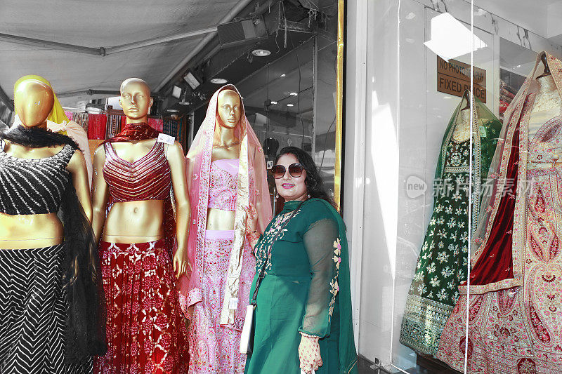 漂亮的印度女士站在商店里的女性模特旁边的肖像