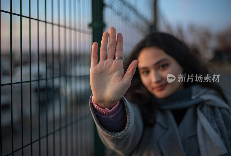 年轻的黑发女孩的肖像。
年轻女孩在看镜头时举手。