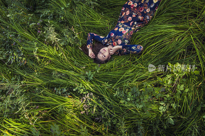 美丽的年轻女子穿着衣服躺在草地上