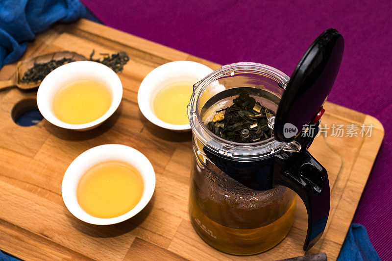 青木背景上的玻璃茶壶装绿茶，配香椿和茶杯