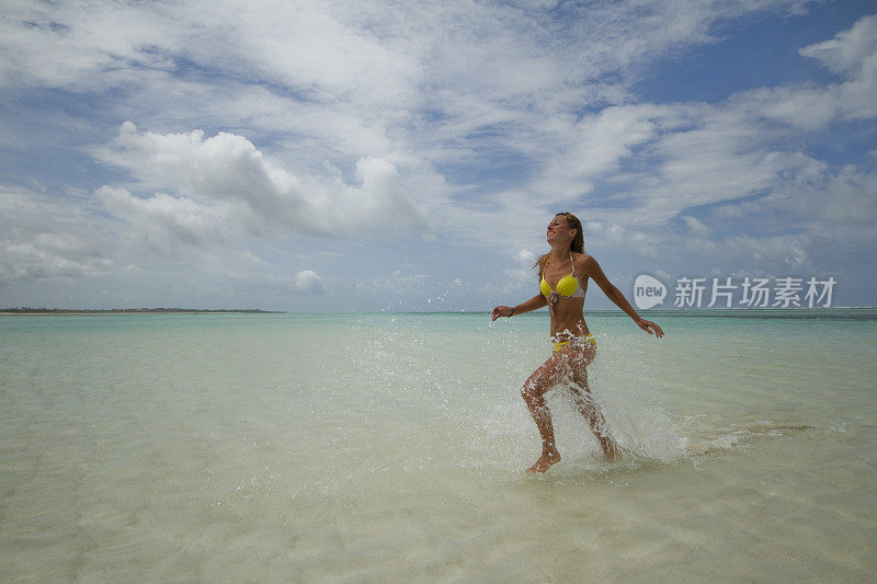 年轻女子在海滩上冲进水里热带气候