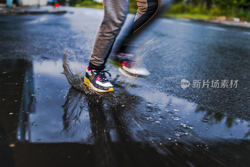 在雨天，年轻女子在沥青操场上跑步