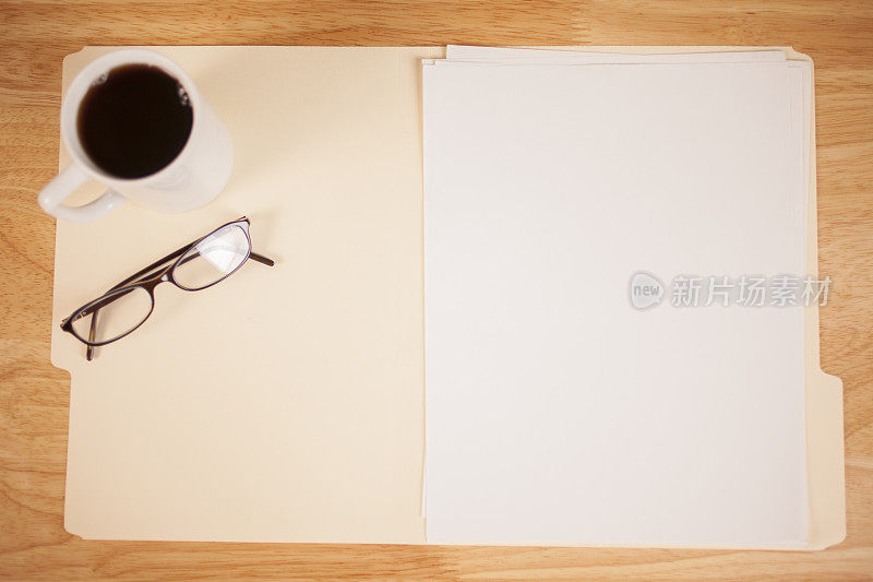 打开空白纸的马尼拉文件夹。桌子上。眼镜、咖啡。
