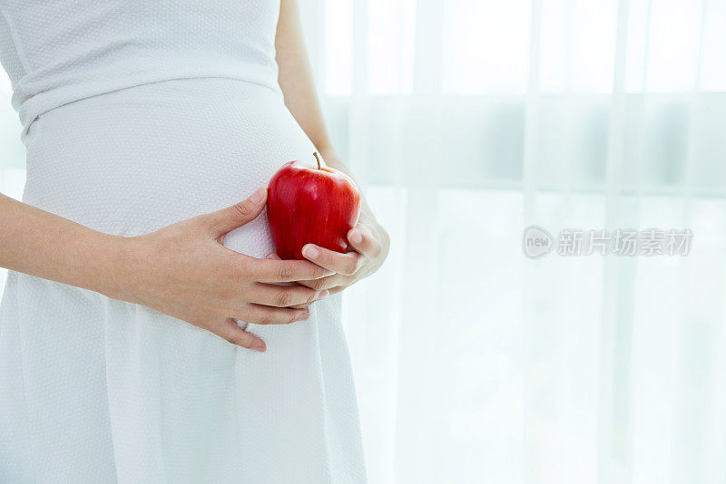 一个孕妇拿着一个红苹果