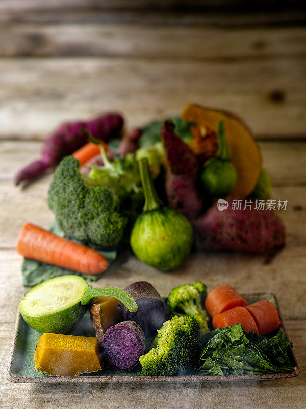 新鲜的清蒸蔬菜放在长方形的绿色瓷盘上，直接从蒸笼出来。