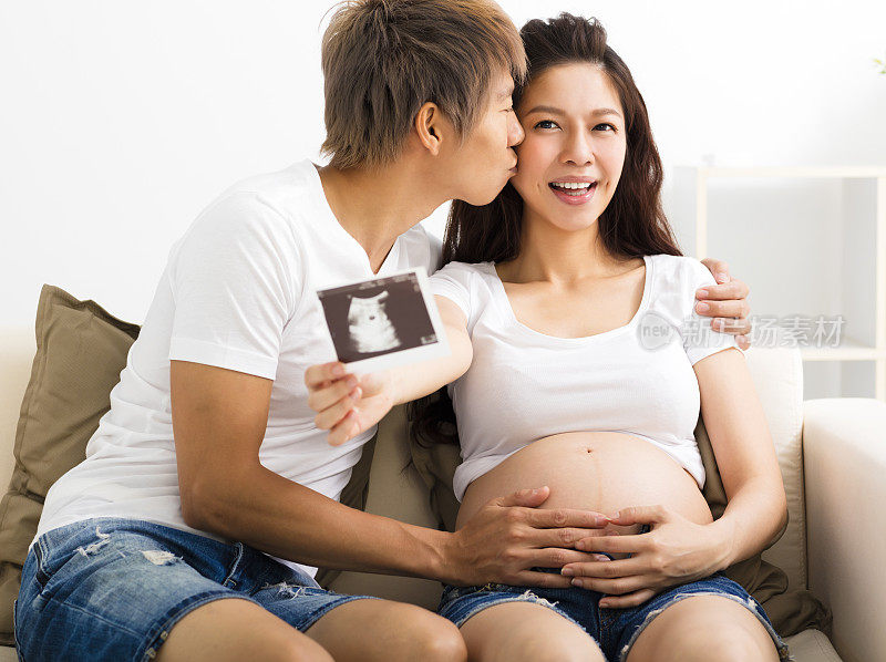 幸福的怀孕和丈夫展示超声波图像