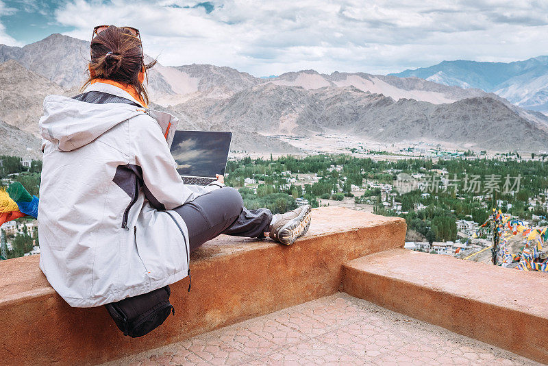 带着笔记本电脑的游客坐在山谷的顶视图上