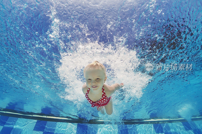 在游泳池里溅起水花在水下游泳的孩子