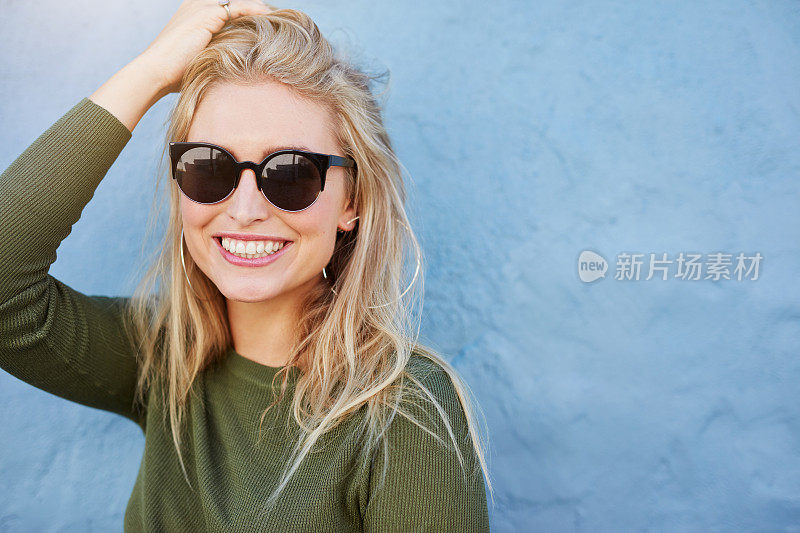 年轻漂亮的女人戴着太阳镜微笑着