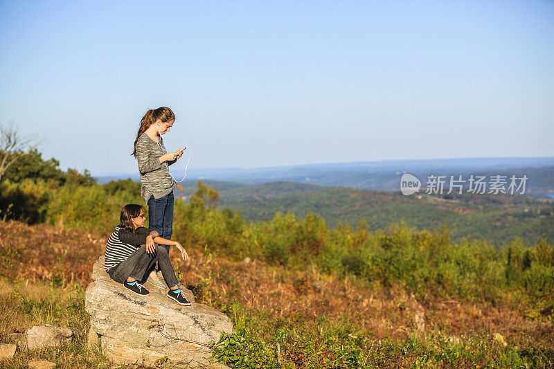 两个十几岁的女孩在山顶拍照