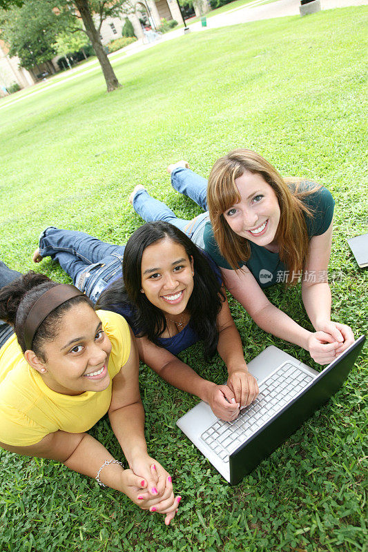 大学校园草坪上的朋友和他们的笔记本电脑