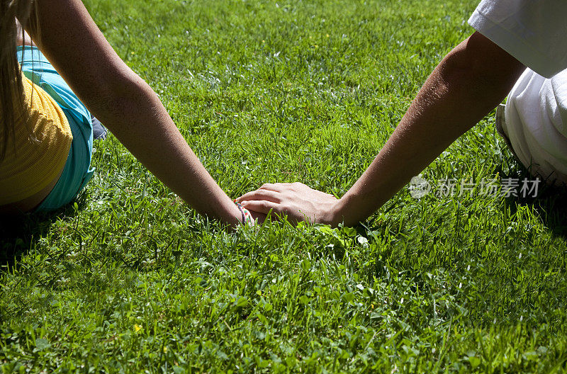 一对十几岁的异性恋夫妇手牵着手在绿草地上