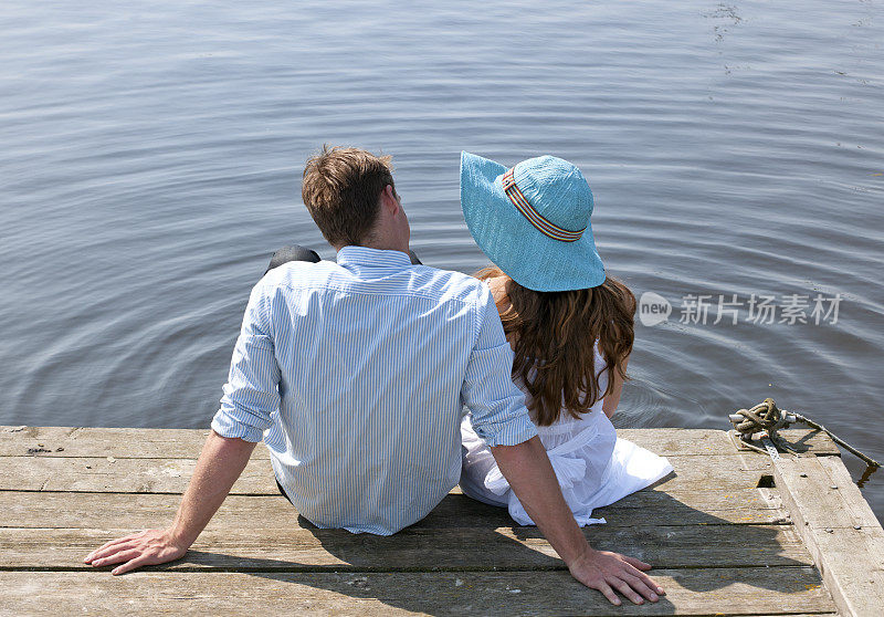 一对年轻夫妇坐在码头上
