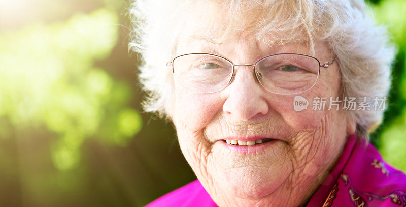 微笑的老年妇女享受生活在阳光灿烂的花园
