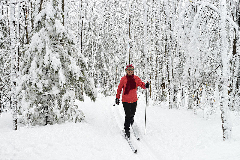 穿红色衣服的女人在白雪覆盖的森林里滑雪