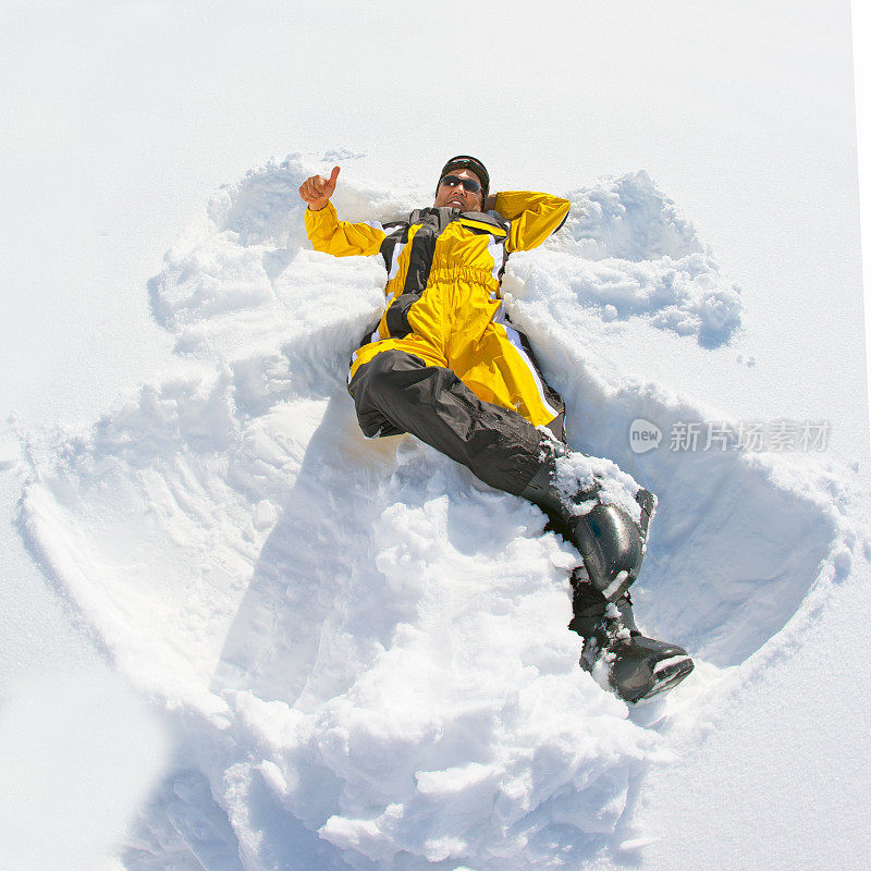 快乐的滑雪者躺在雪地上，竖起大拇指