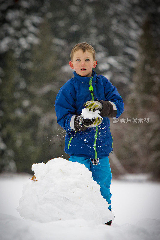 男孩建造雪人。