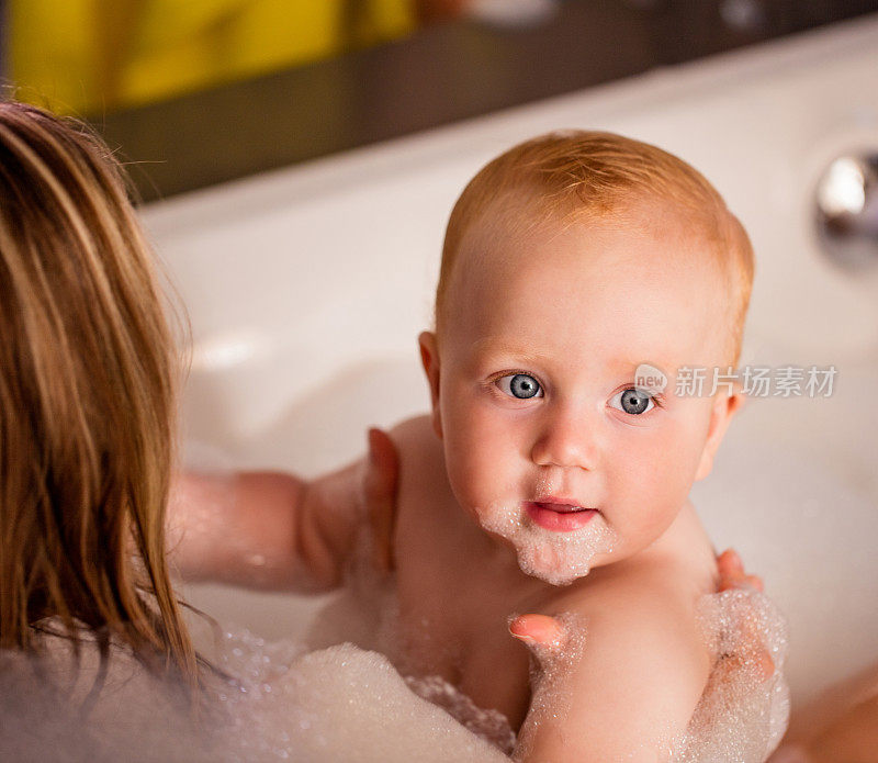 现代妈妈和婴儿女儿一起洗泡泡浴