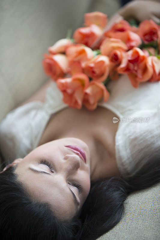 年轻女子躺着，手里拿着花