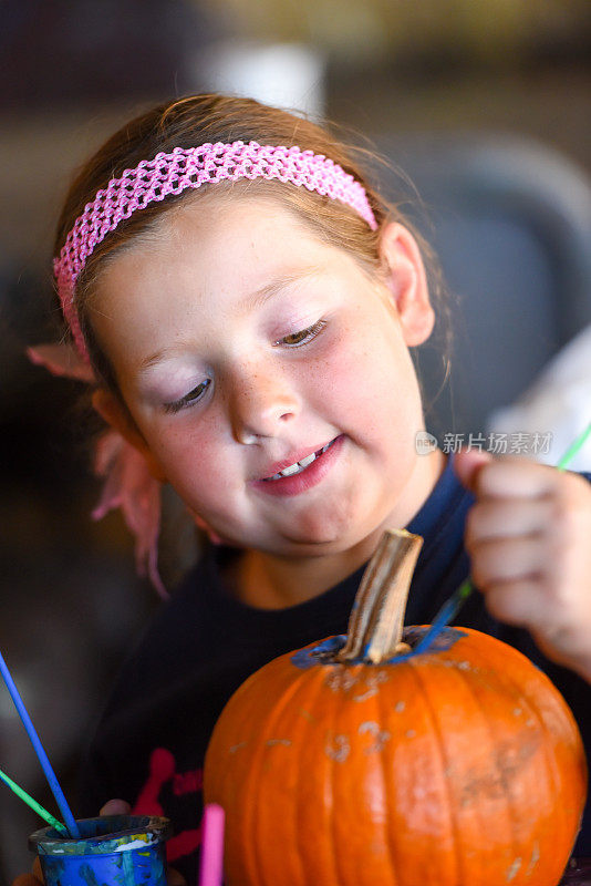 小女孩微笑着画一个南瓜