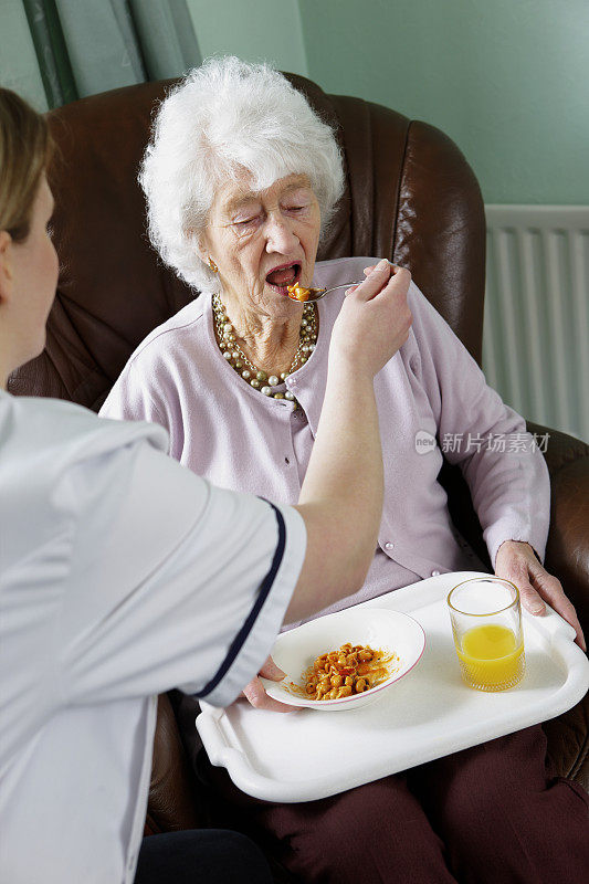 在养老院，护士为老年妇女提供膳食