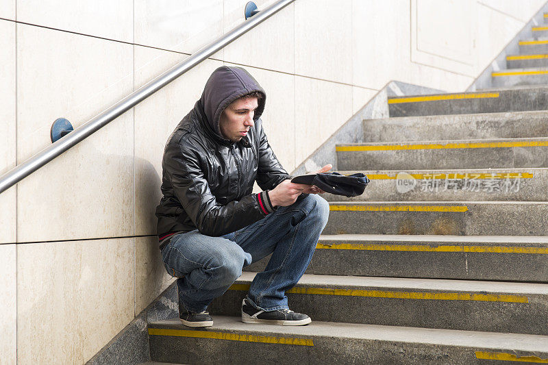 年轻的街头乞丐……可能是个瘾君子，在楼梯上乞讨