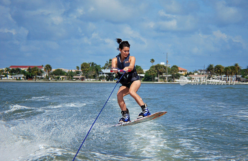 运动的年轻女子在Wakeboard跳