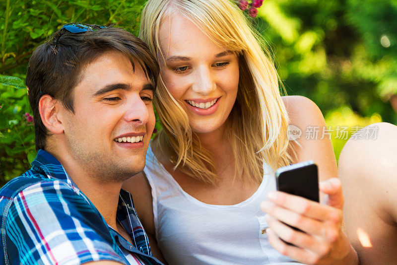 一对年轻夫妇看着智能手机一起微笑。