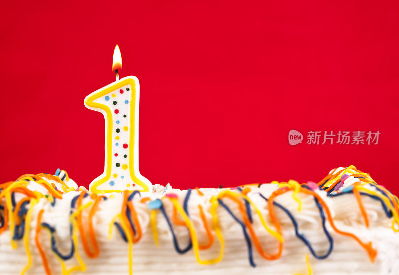 用燃烧的1号蜡烛装饰生日蛋糕。红色的背景。