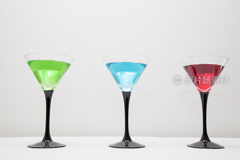 三款优雅的鸡尾酒，绿，蓝，红，素色背景