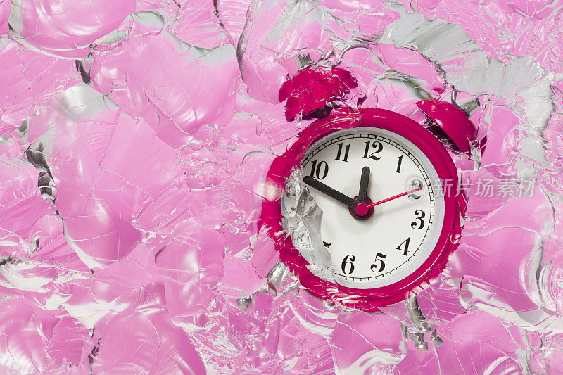 闹钟在冰块粉红色的背景