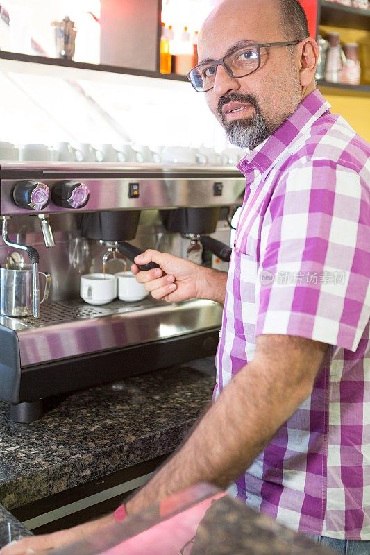 企业主摆出在他的机器里制作浓缩咖啡的姿势