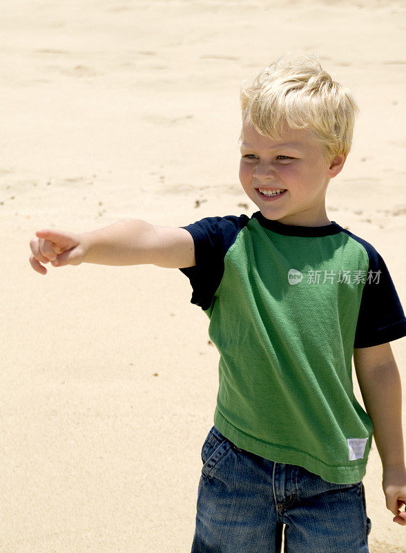 一个男孩在沙滩上指着什么东西